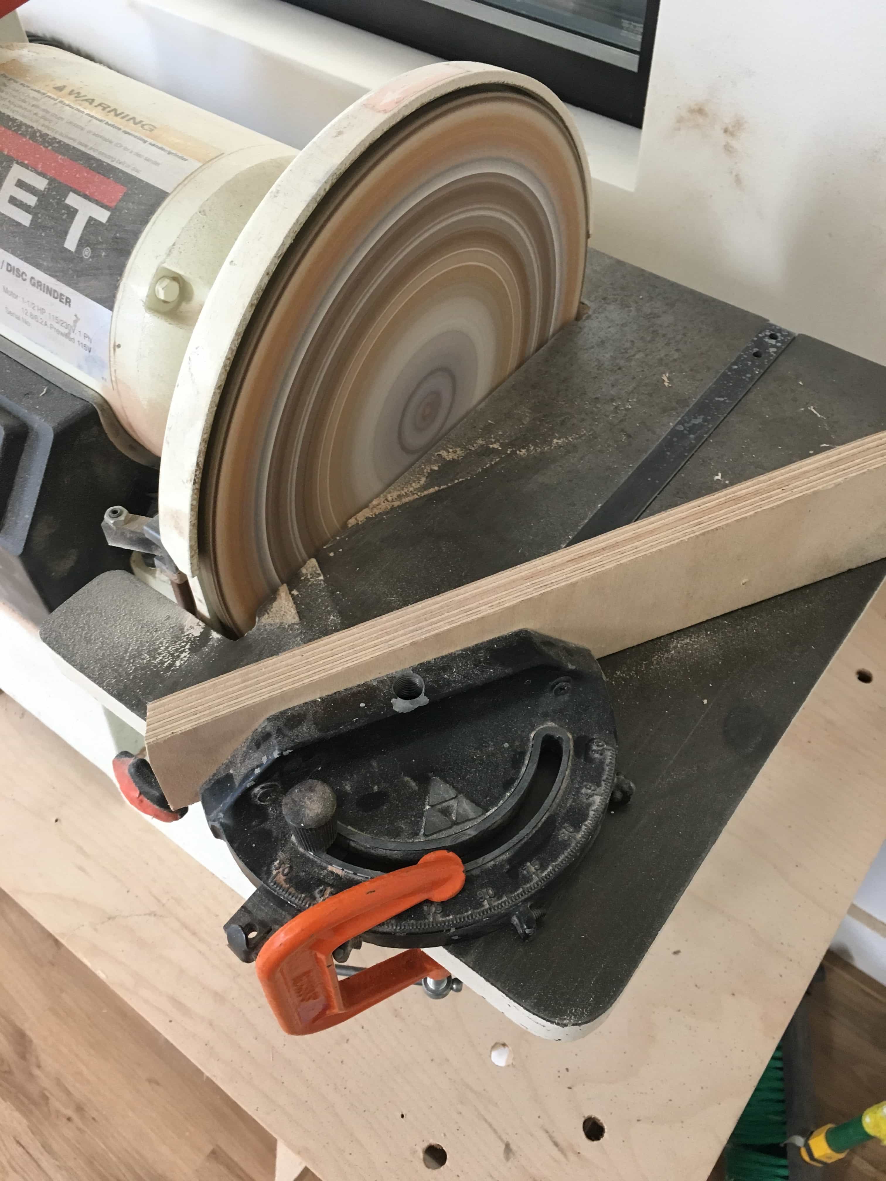 Jig lined up at an angle to sanding wheel.
